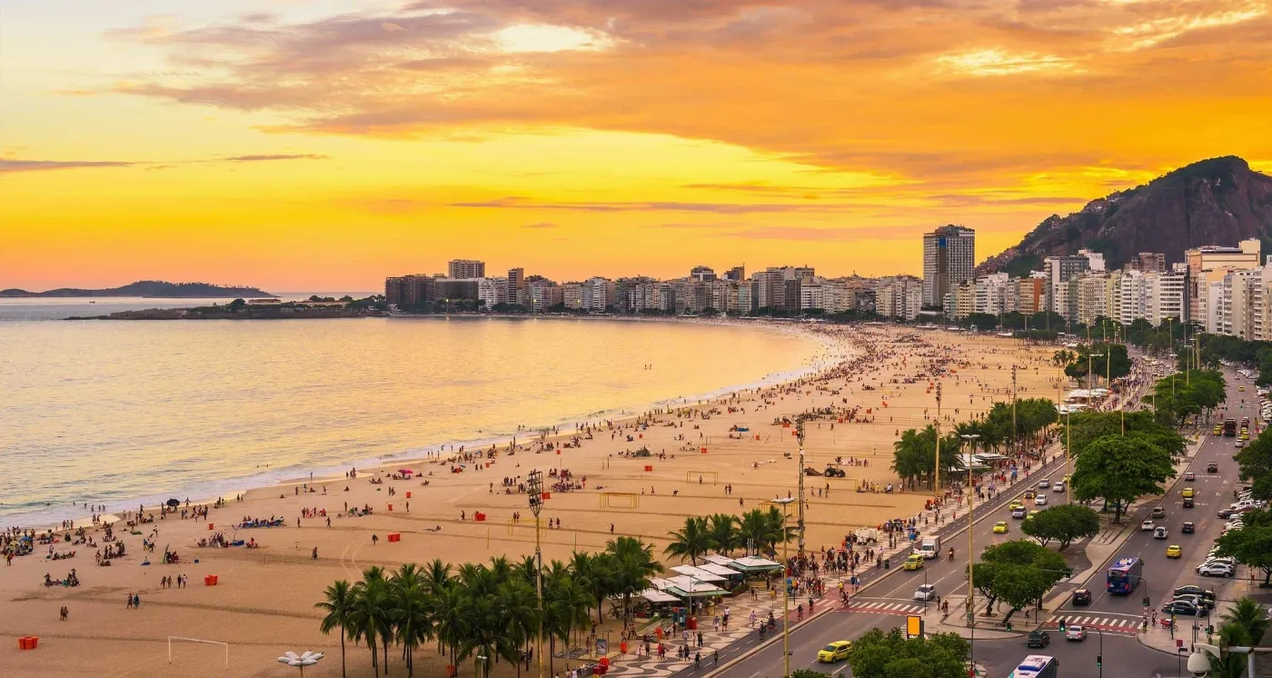 Copacabana beach in Rio de Janeiro at sunset, the curve of the bay lined with apartment blocks and the Avenida Atlântica promenade