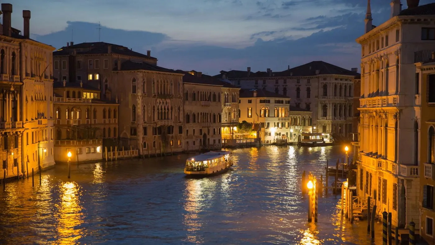 Venice at night: a vaporetto on the Grand Canal between lit palazzi, the cheapest way to see the city from the water