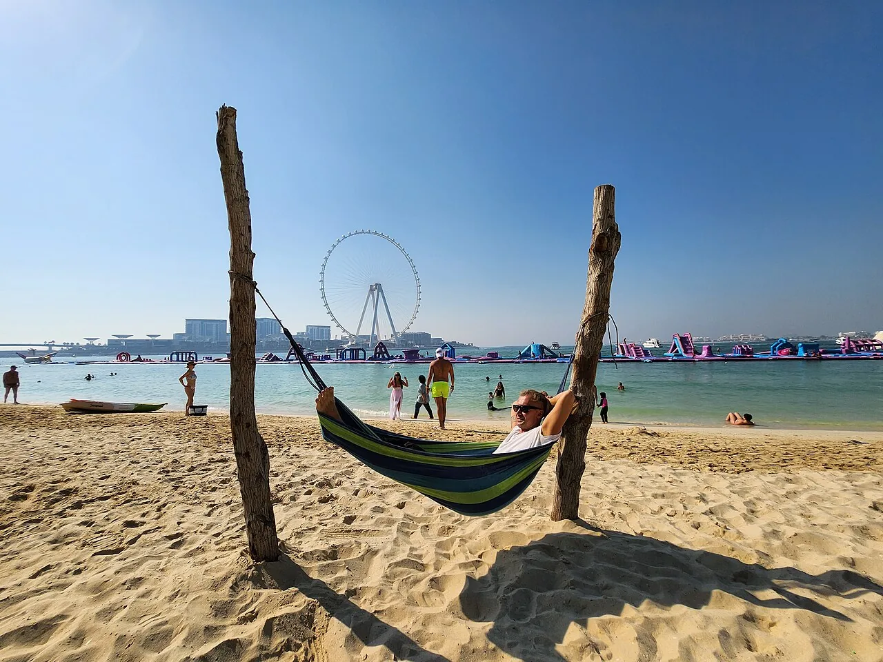 JBR Beach in Dubai, with a hammock strung between posts on the sand and the marina skyline across the water