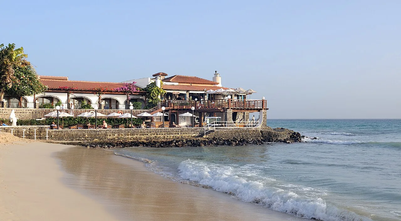 A praia de Santa Maria, na ilha do Sal, com um hotel sobre a rocha e as ondas a chegar à areia