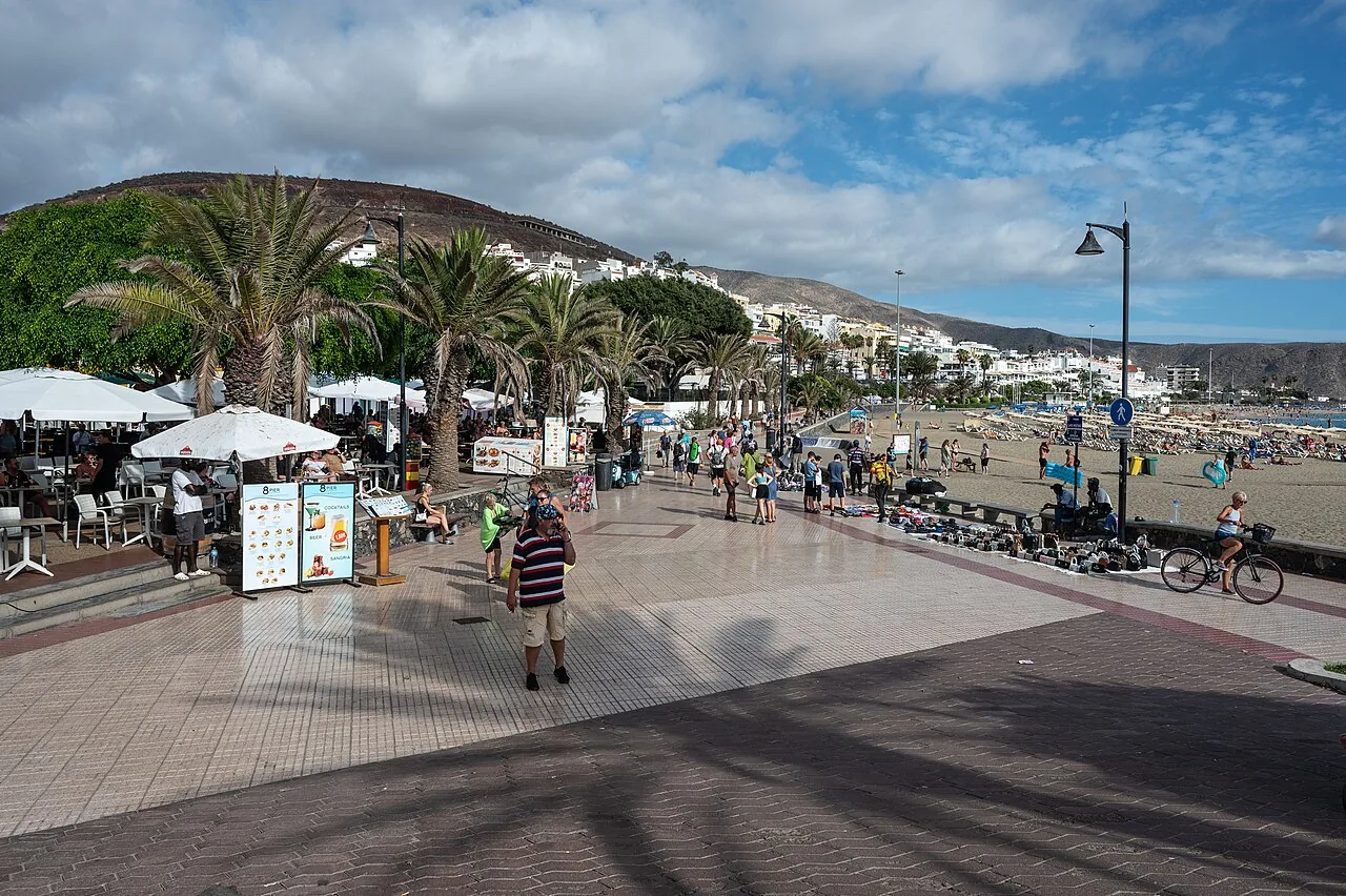 The promenade at Playa de las Vistas in southern Tenerife, with palms, cafés and the beach in the same afternoon